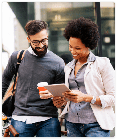 Two people looking at a tablet outside a glass building