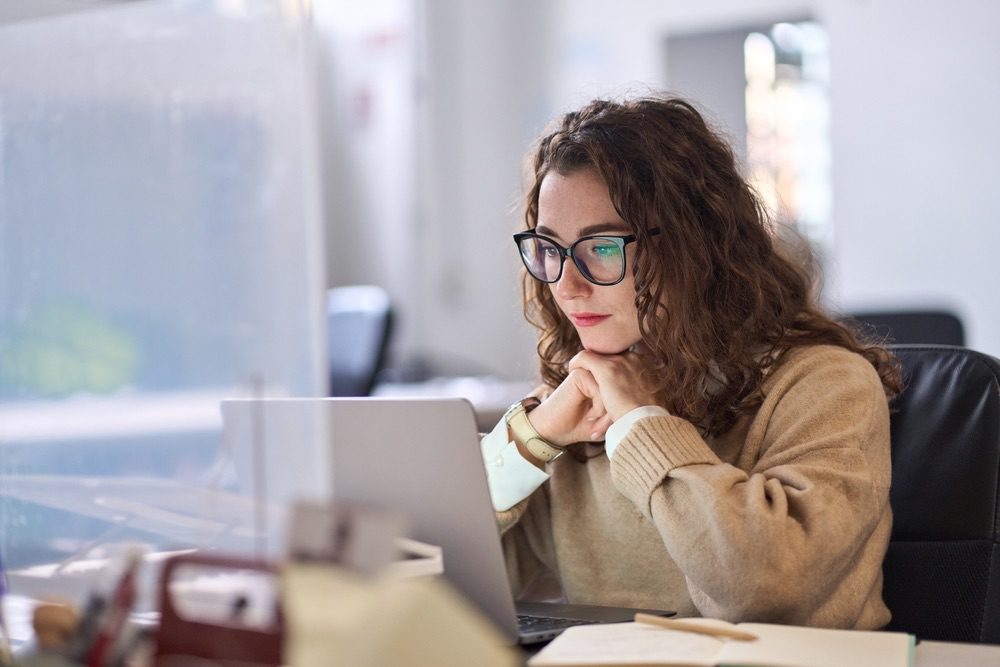 Young serious busy professional business woman employee using laptop doing research